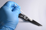 La imagen muestra una mano con guante de latex sosteniendo un hisopo. Ese hisopo toca un cuchillo, del cual se están obteniendo restos biológicos